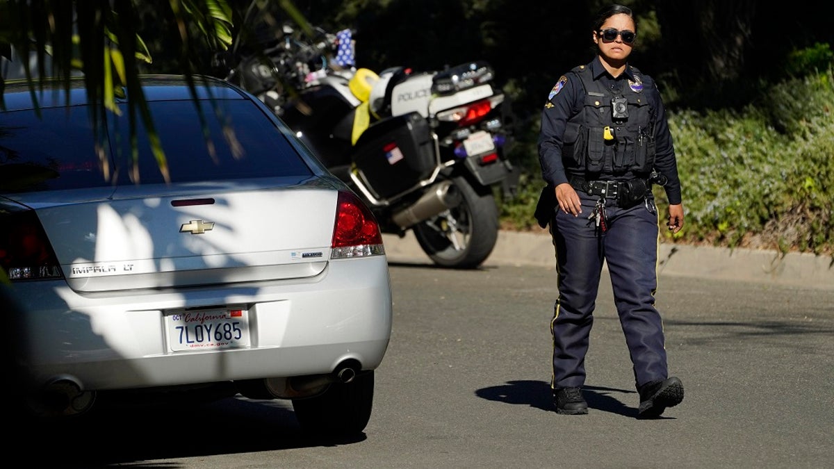 A police officer walks down Maytor Place in the Trousdale Estates section of Beverly Hills, Calif., Wednesday, Dec. 1, 2021. Jacqueline Avant, the wife of music legend Clarence Avant, was fatally shot in the neighborhood early Wednesday.