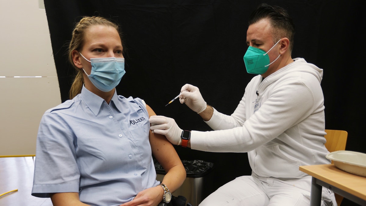 A policewoman gets a booster vaccination against the coronavirus and the COVID-19 disease in Hilden, Germany, Thursday, Dec. 2, 2021. (David Young/dpa via AP)