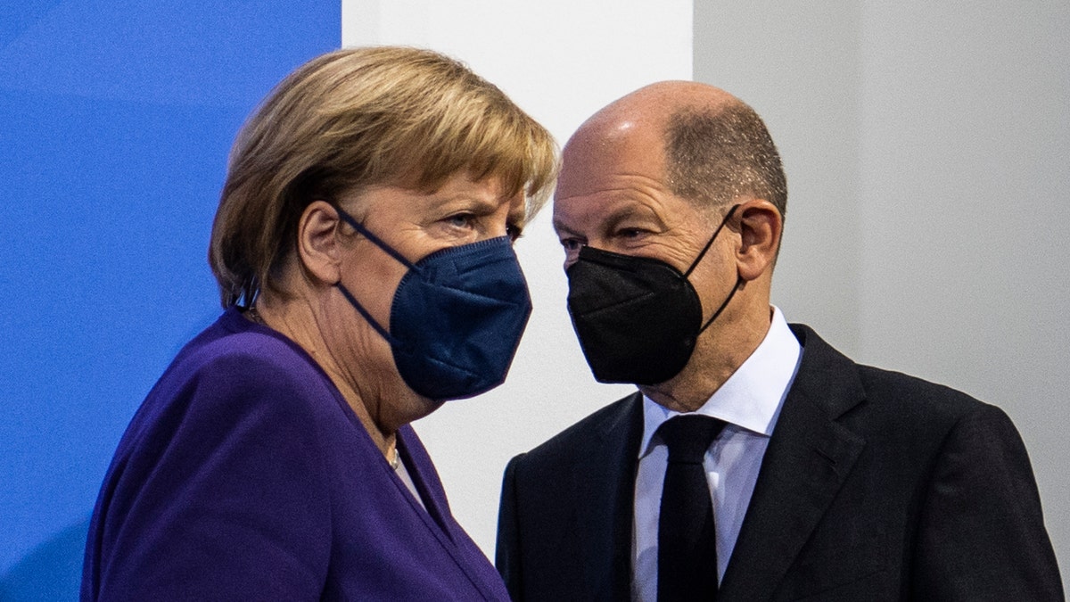 German Chancellor Angela Merkel, left, and Finance Minister Olaf Scholz arrive for a press conference following a meeting with the heads of government of Germany's federal states at the Chancellery in Berlin, Thursday, Dec. 2, 2021.  (John Macdougall/Pool Photo via AP)