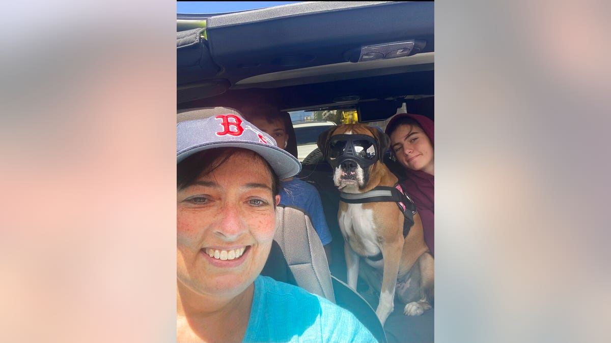 This 2021 photo provided by Cheri Burness shows Burness and her family, including dog Lilikoi, in car in Honolulu. Hundreds of military families living near Pearl Harbor have complained of stomach pain, nausea and other health ailments amid concerns the Navy's water system may have been contaminated by a fuel leak.(Cheri Burness via AP)