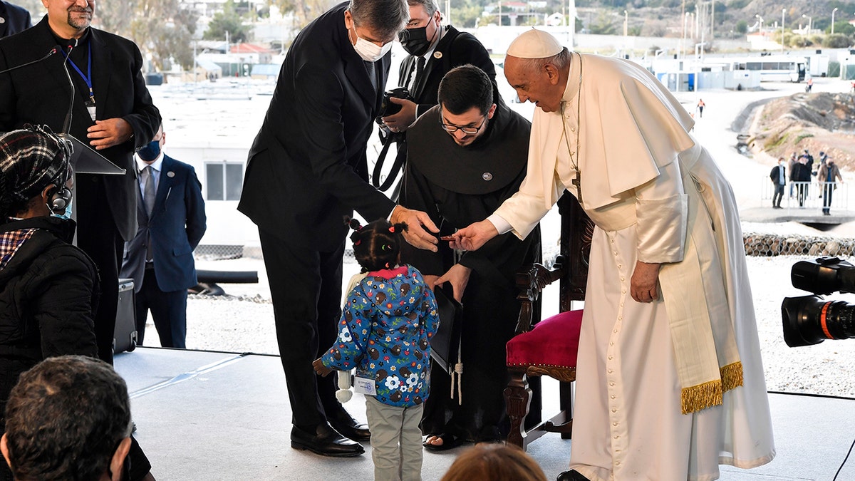 Pope Francis meets a child during a ceremony at the Karatepe refugee camp, on the northeastern Aegean island of Lesbos, Greece, Sunday, Dec. 5, 2021. 