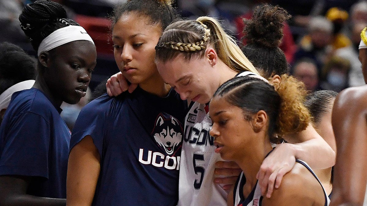 Connecticut's Paige Bueckers, center, is helped off the court by Amari DeBerry, left, and Evina Westbrook in the second half of an NCAA college basketball game against Notre Dame on Sunday, Dec. 5, 2021 in Storrs, Connecticut.