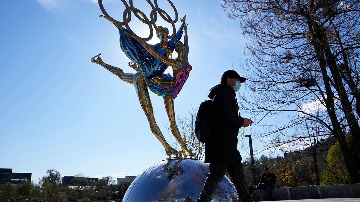 A visitor to the Shougang Park walks past a sculpture for the Beijing Winter Olympics in Beijing, China, Tuesday, Nov. 9, 2021. (AP Photo/Ng Han Guan)