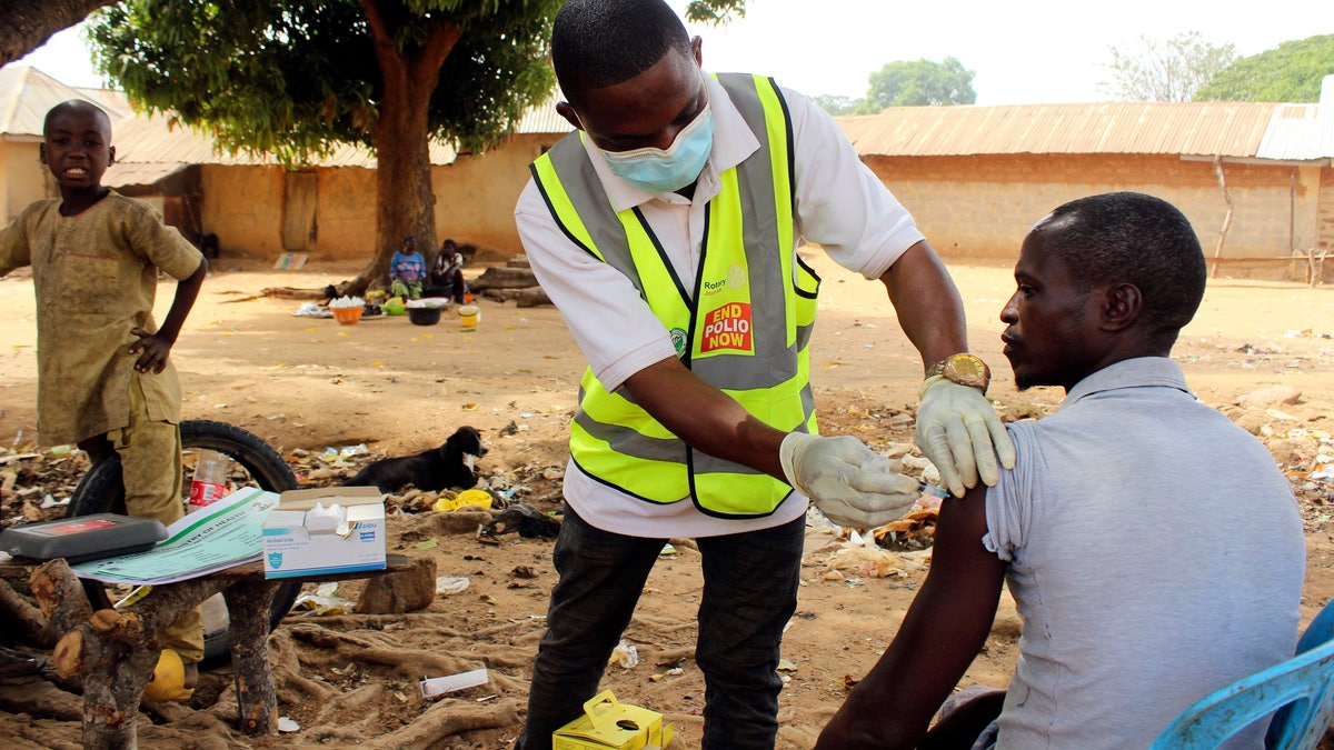 Yunusa Bawa, a community health worker, injects a man with AstraZeneca coronavirus vaccine in Sabon Kuje on the outskirts of Abuja, Nigeria, Monday, Dec 6, 2021. (AP Photo/Gbemiga Olamikan)