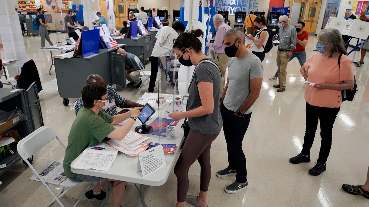 Voters sign in at Frank McCourt High School for New York's party primaries, June 22, 2021, in New York. New York City, long a beacon for immigrants, is on the cusp of becoming the largest place in the U.S. to give noncitizens the right to vote. Legally documented, voting-age noncitizens, who comprise nearly one in 10 of the city's 8.8 million inhabitants, would be allowed to cast votes in elections to pick the mayor, City Council members and other municipal officeholders under a bill nearing approval. (AP Photo/Richard Drew, File)