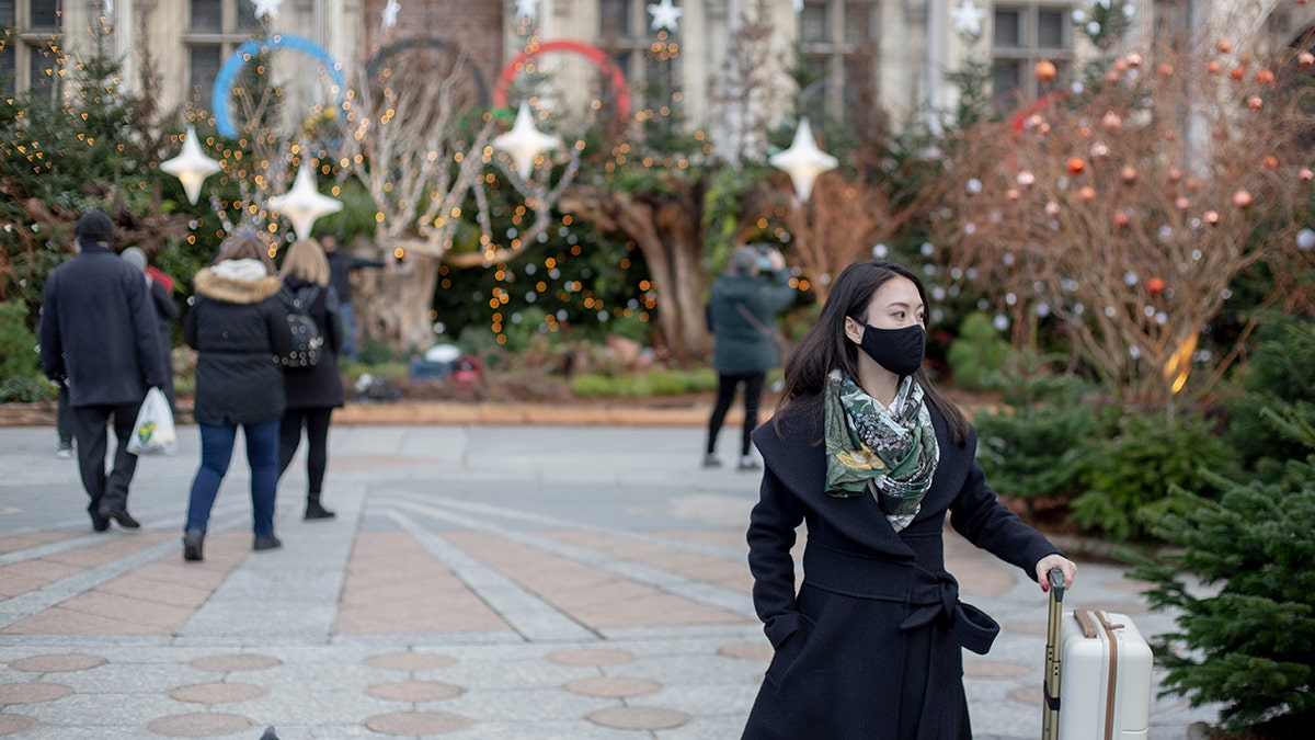 A woman wears a face mask to prevent the spread of the COVID-19 as she walk past in front the City Hall, in Paris, Wednesday, Dec. 8, 2021. (AP Photo/Rafael Yaghobzadeh)