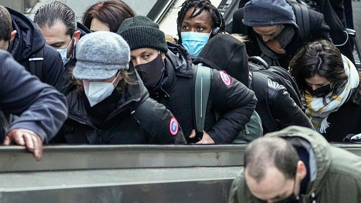 Commuters wearing face masks to protect against COVID-19 ride an escalator at La Defense business district in Paris, Wednesday, Dec. 8, 2021.  (AP Photo/Michel Euler)
