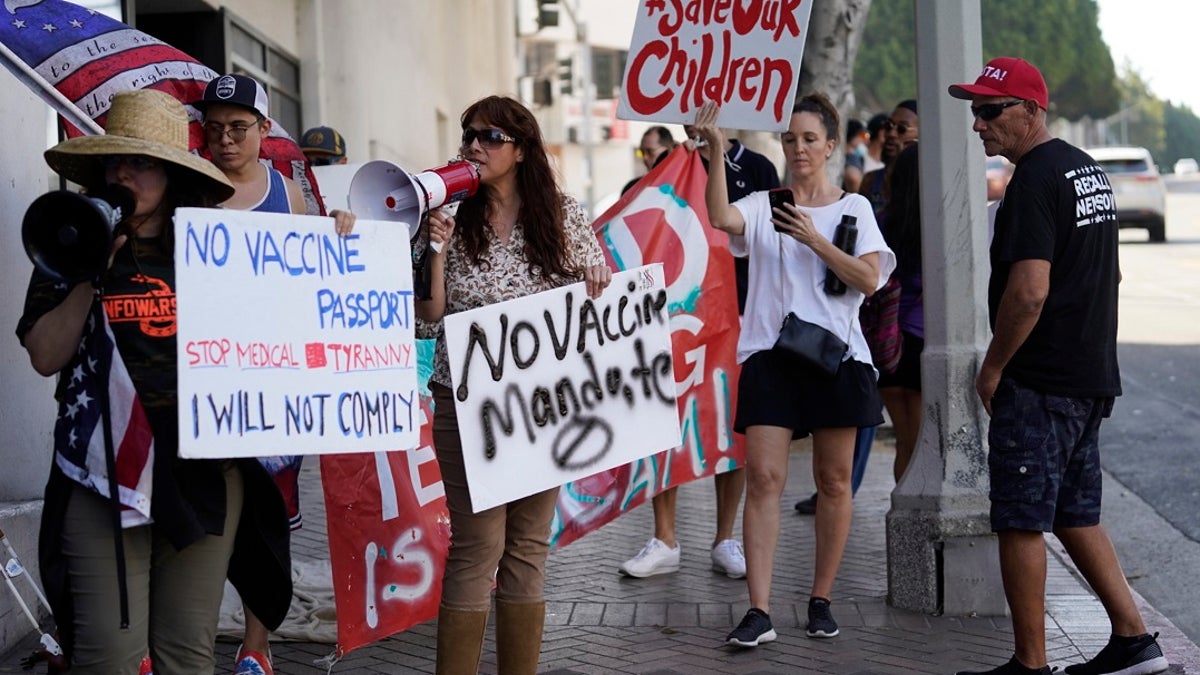 Anti-vaccine mandate protesters rally outside the garage doors of the Los Angeles Unified School District, LAUSD headquarters in Los Angeles. Nearly 500 Los Angeles Unified School District employees were fired this week. (AP Photo/Damian Dovarganes, File)