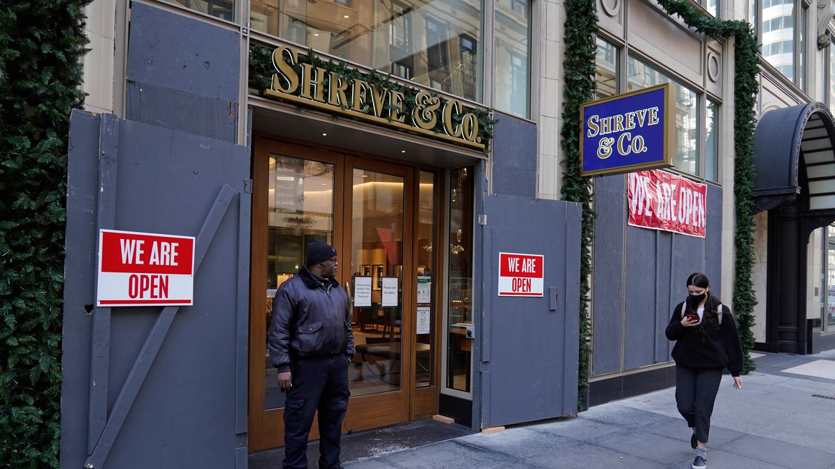 A security guard stands outside the heavily boarded Shreve & Co. jewelry store in San Francisco, Thursday, Dec. 2, 2021. 