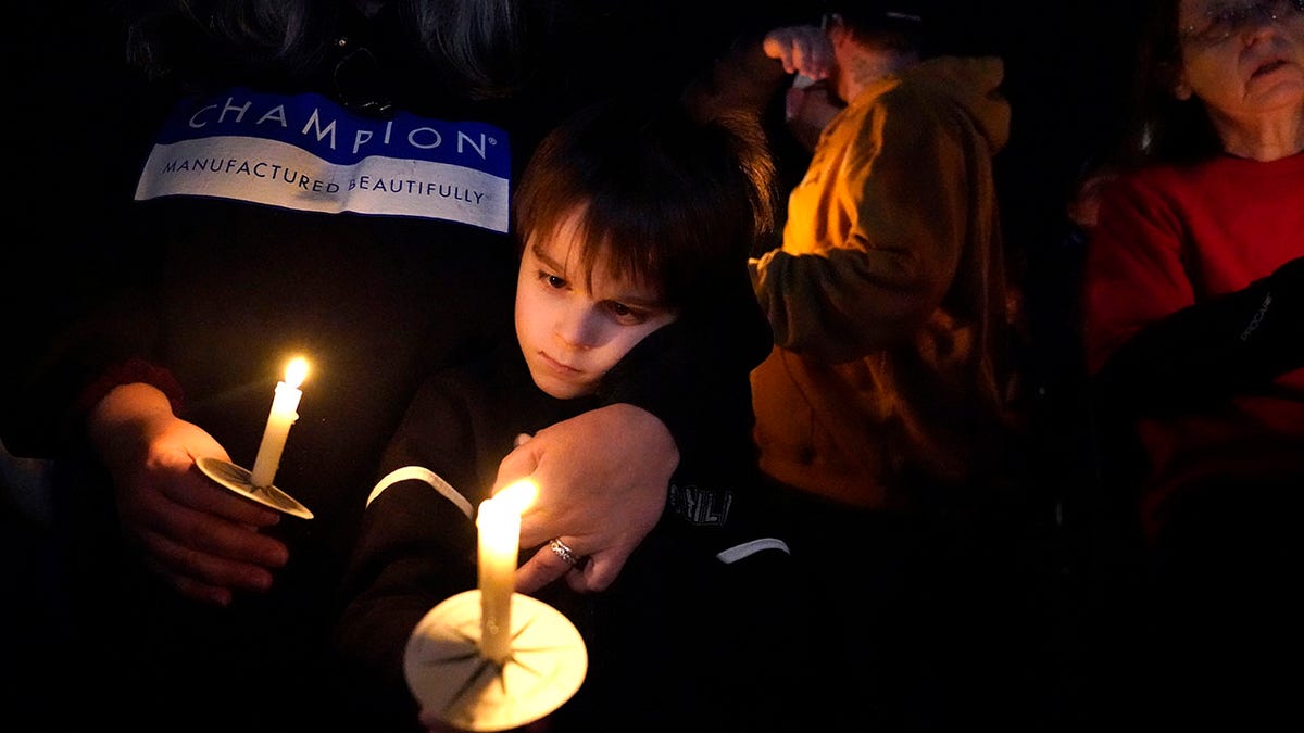 A young boy holds a candle during a vigil in the aftermath of tornadoes that tore through the region several days earlier, in Mayfield, Ky., late Tuesday, Dec. 14, 2021.