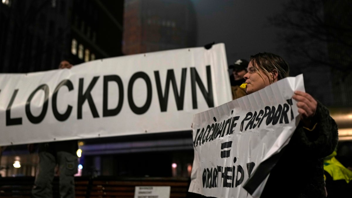 A protestor holds a banner during a small anti-COVID restriction demonstration in the Hague, the Netherlands, Saturday, Dec. 18, 2021. (AP Photo/Peter Dejong)