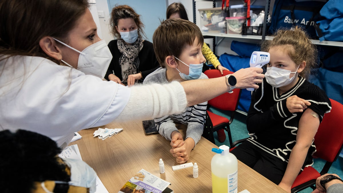 A medical staffer takes the temperature to a child in a vaccine center in Sélestat, eastern France, Tuesday, Dec. 21, 2021. (AP Photo/Jean-Francois Badias)
