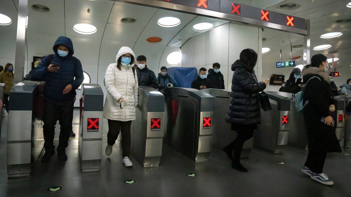 Commuters wearing face masks to protect against COVID-19 exit a subway station in the central business district in Beijing, Thursday, Dec. 23, 2021. (AP Photo/Mark Schiefelbein)