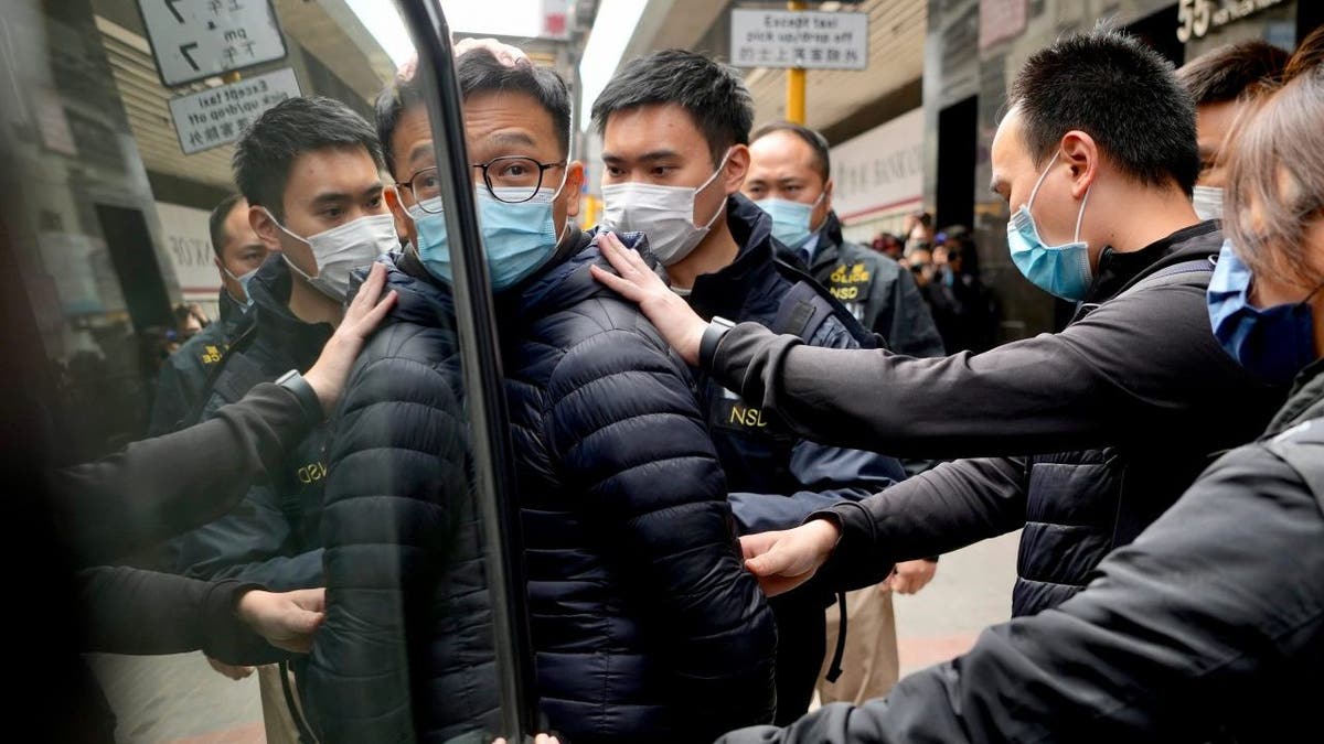 Editor of Stand News' Patrick Lam, center, is escorted by police officers into a van after they searched evidence at his office in Hong Kong, Wednesday, Dec. 29, 2021. Hong Kong police raided the office of the online news outlet on Wednesday after arresting several people for conspiracy to publish a seditious publication.