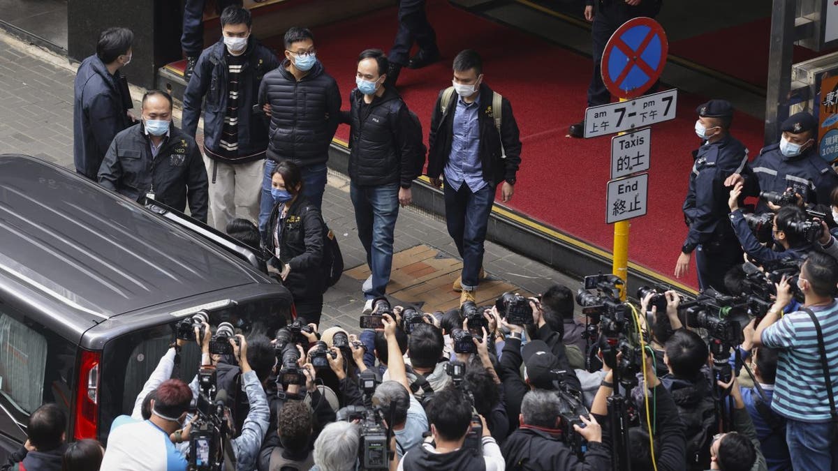 Editor of Stand News Patrick Lam, fourth from left, is escorted by police officers into a van after they searched for evidence at his office in Hong Kong, Wednesday, Dec. 29, 2021. 