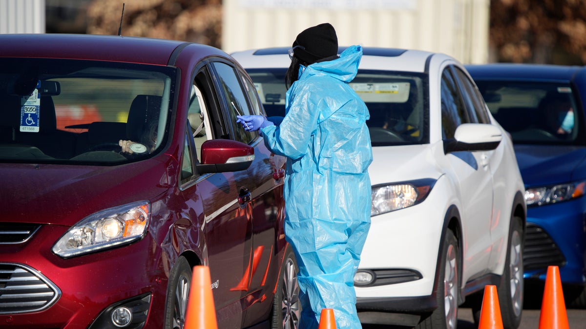 A medical technician performs a nasal swab test on a motorist queued up in a line at a COVID-19 testing site near All City Stadium, Thursday, Dec. 30, 2021, in southeast Denver. (AP Photo/David Zalubowski)