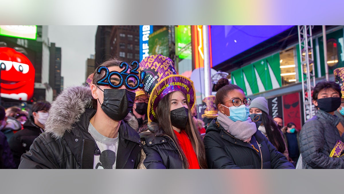 From left, Christopher Gicostanzo of Canada, Emma Marianni and Zoe Fauchi, both from Paris, France, stand in Times Square while waiting for the annual New Year's Eve ball drop in New York City on Friday, Dec. 31, 2021. (AP Photo/Ted Shaffrey)