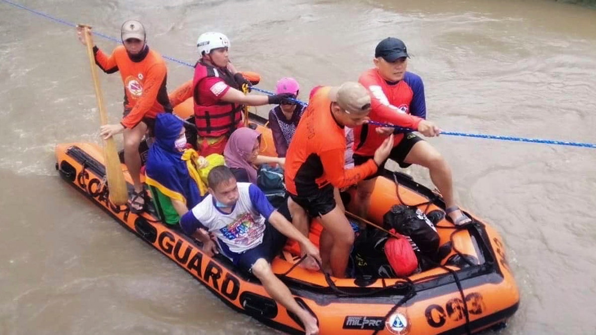 In this handout photo provided by the Philippine Coast Guard, residents ride a rubber boat along floods caused by Typhoon Rai as they are evacuated to higher grounds in Cagayan de Oro City, southern Philippines on Thursday, Dec. 16, 2021. 