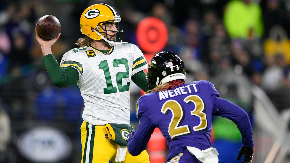 Green Bay Packers quarterback Aaron Rodgers (12) throws to a receiver as he is pressured by Baltimore Ravens cornerback Anthony Averett in the first half of an NFL football game, Sunday, Dec. 19, 2021, in Baltimore.