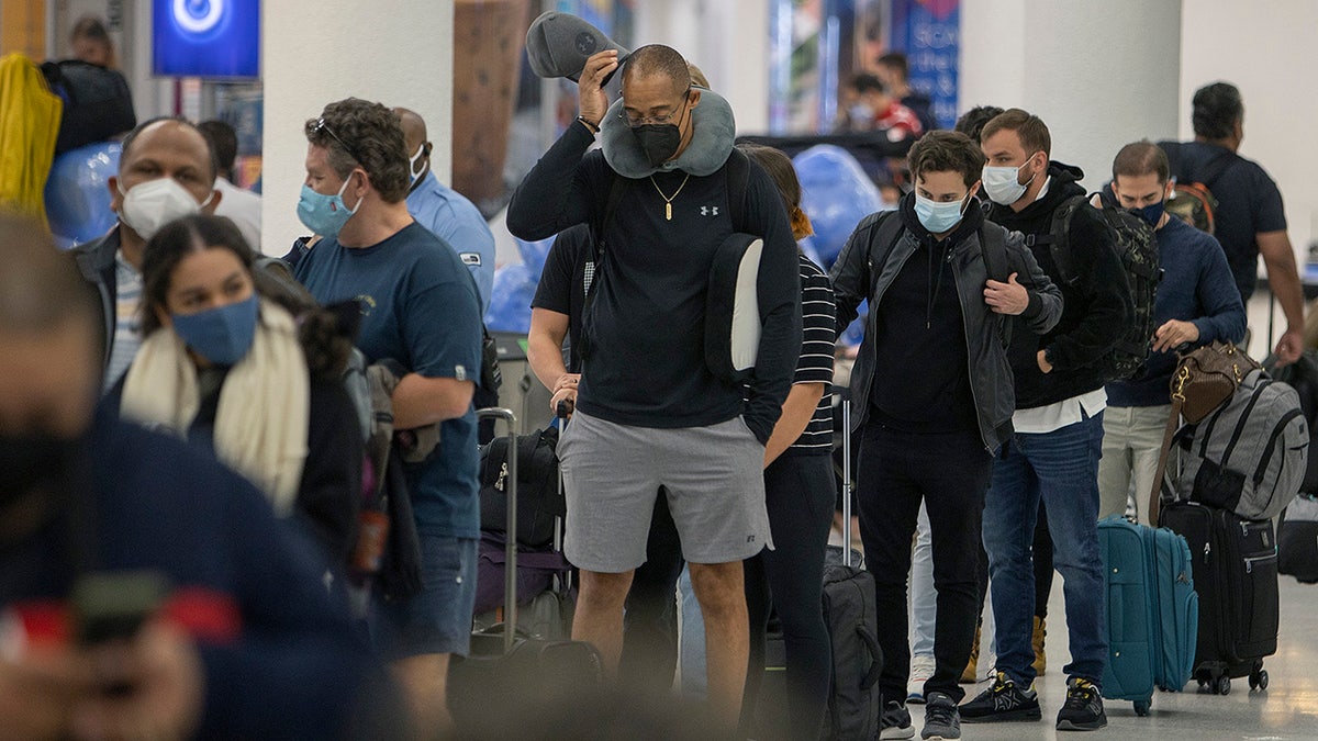 Travelers make their way through Miami International Airport on Dec. 23, 2021, in Miami. U.S. holiday travel numbers are rivaling 2019 amid an omicron variant surge, and President Biden is rescinding his travel ban on eight African countries where the variant first spread. (Photo by Joe Raedle/Getty Images)