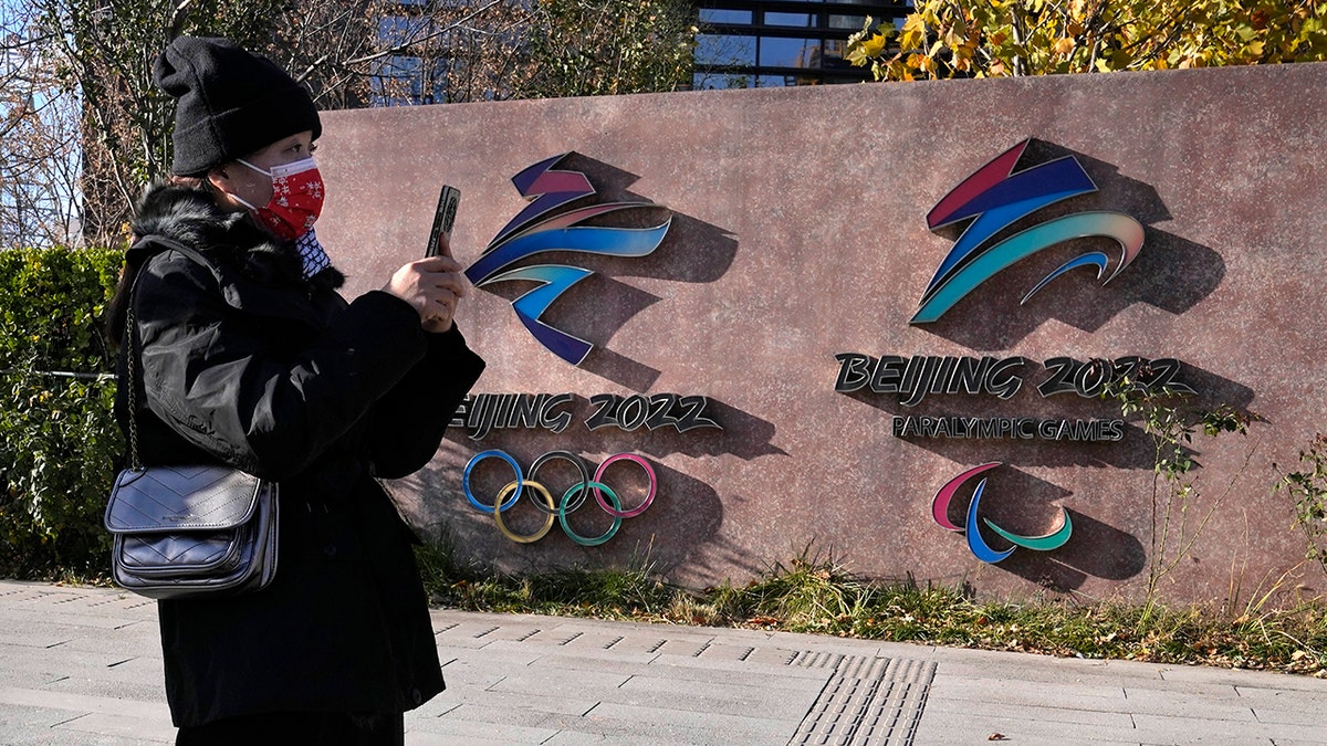 A visitor to the Shougang Park walks past the logos for the Beijing Winter Olympics and Paralympics in Beijing, China, Tuesday, Nov. 9, 2021. 