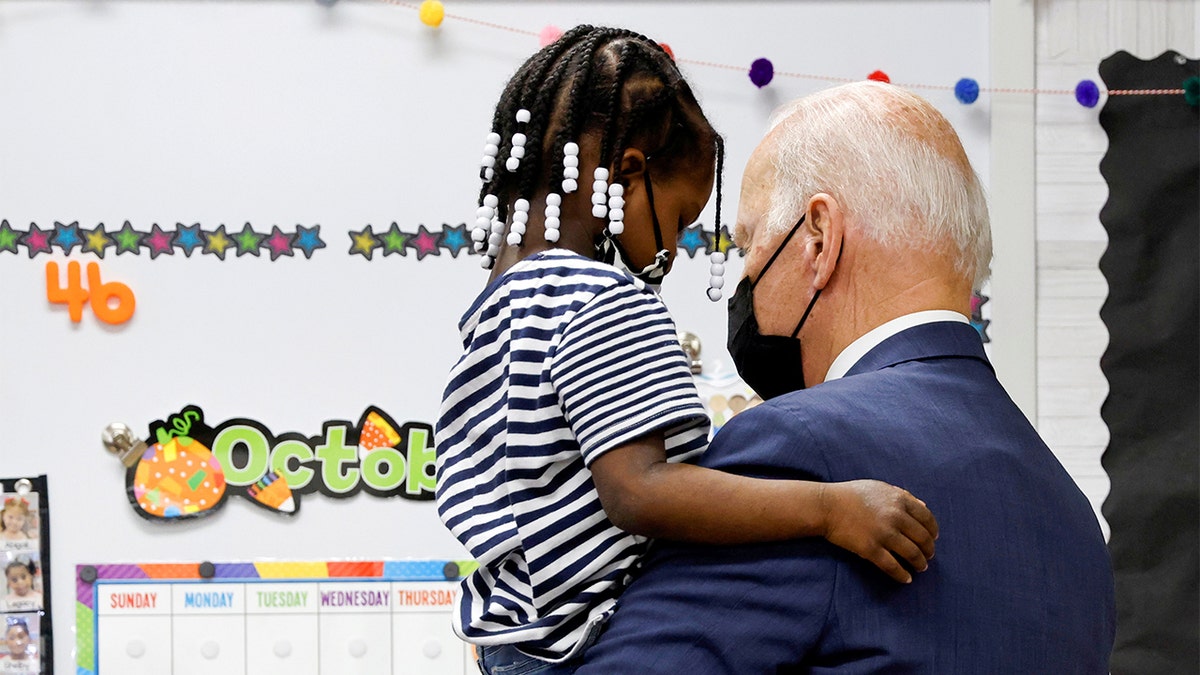 President Biden holds a child as he visits a pre-kindergarten class at East End Elementary School to highlight the early childhood education proposal in his Build Back Better infrastructure agenda in North Plainfield, New Jersey, Oct. 25, 2021.
