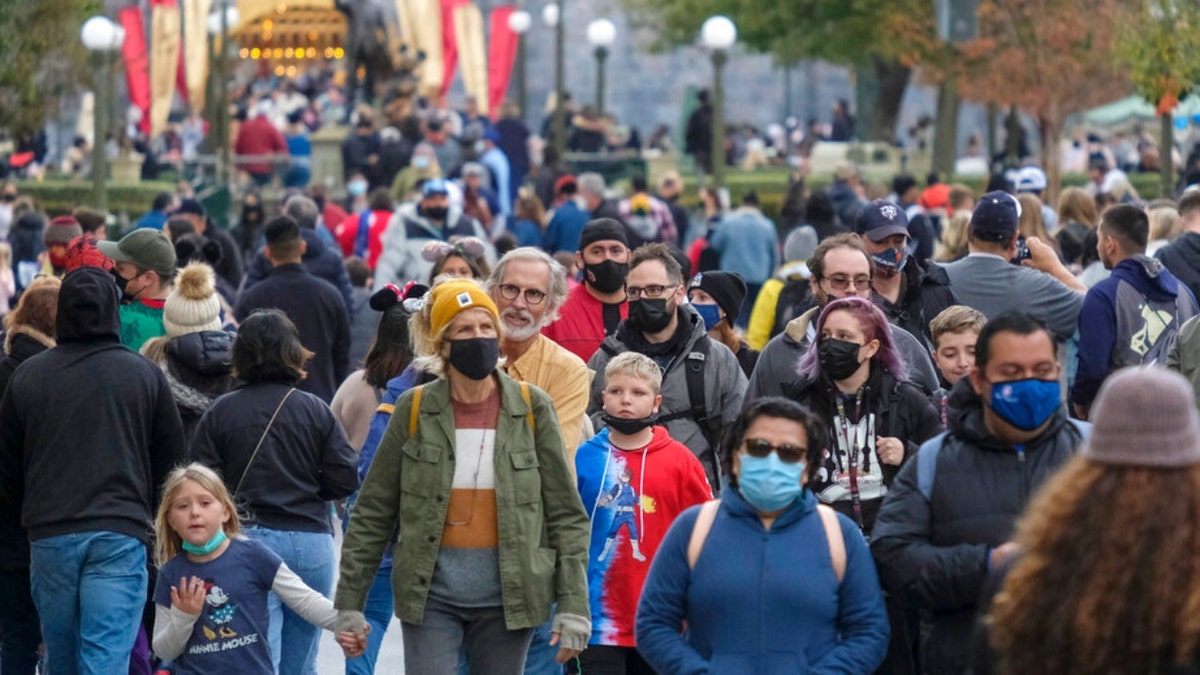 Visitors wearing face masks walk down Main Street USA at Disneyland in Anaheim, Calif., Monday, Dec. 27, 2021. (AP Photo/Ringo H.W. Chiu)