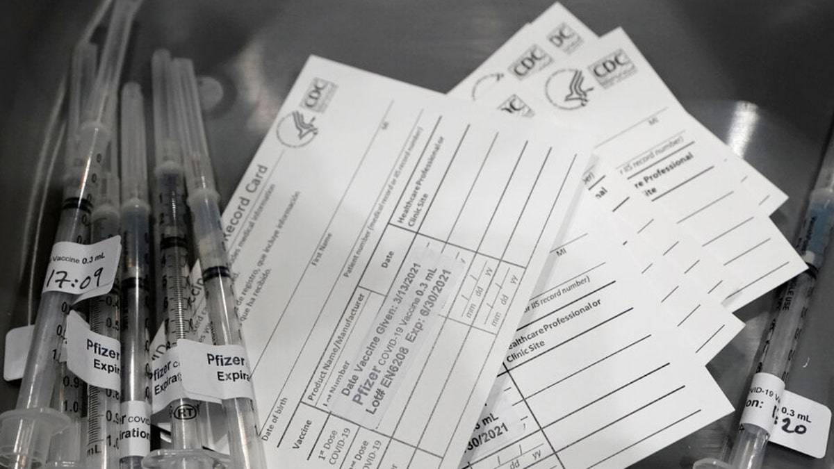 FILE - Syringes with doses of the Pfizer COVID-19 vaccine, are shown next to vaccination cards March 13, 2021, in Seattle. The District of Columbia government is imposing a series of COVID-19 vaccine mandates as it intensifies virus protocols in response to spiraling infection numbers and the march of the omicron variant.