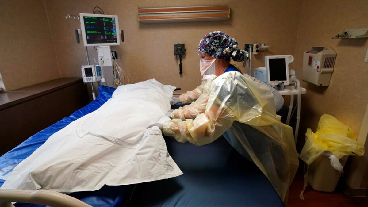 FILE - Medical staff move a COVID-19 patient who died onto a gurney to hand off to a funeral home van, at the Willis-Knighton Medical Center in Shreveport, La., Aug. 18, 2021. The U.S. death toll from COVID-19 topped 800,000, a once-unimaginable figure seen as doubly tragic, given that more than 200,000 of those lives were lost after the vaccine became available practically for the asking.