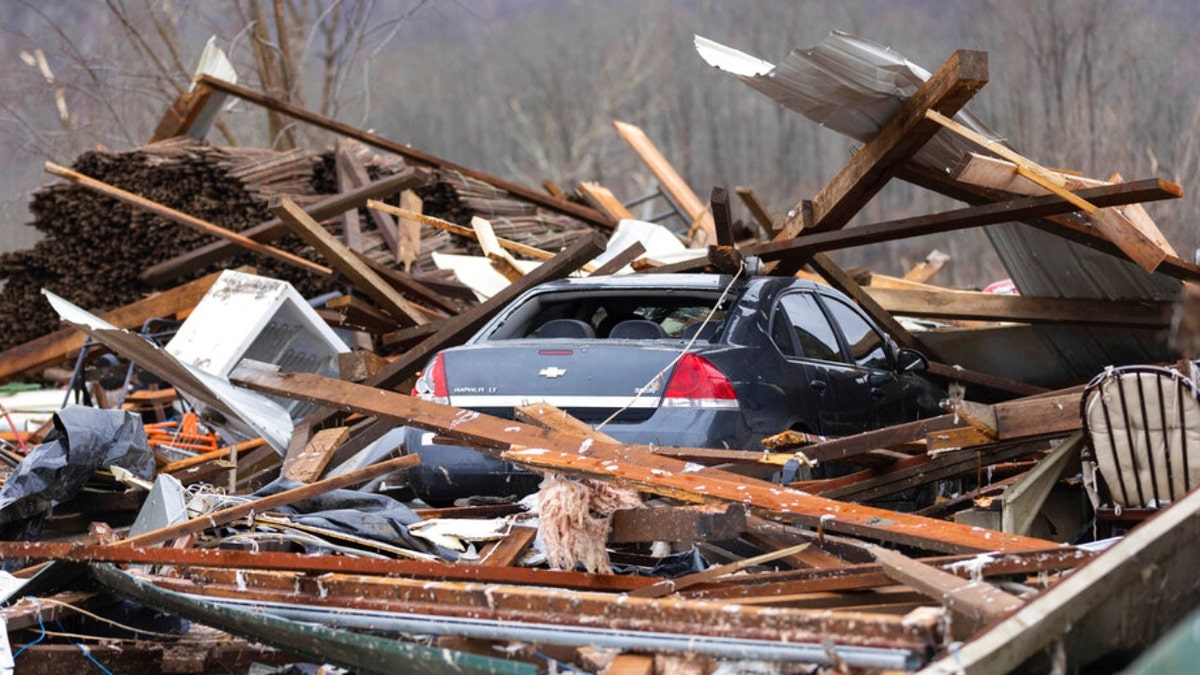 A car sits under a house destroyed by a tornado in Campbellsville, Kentucky