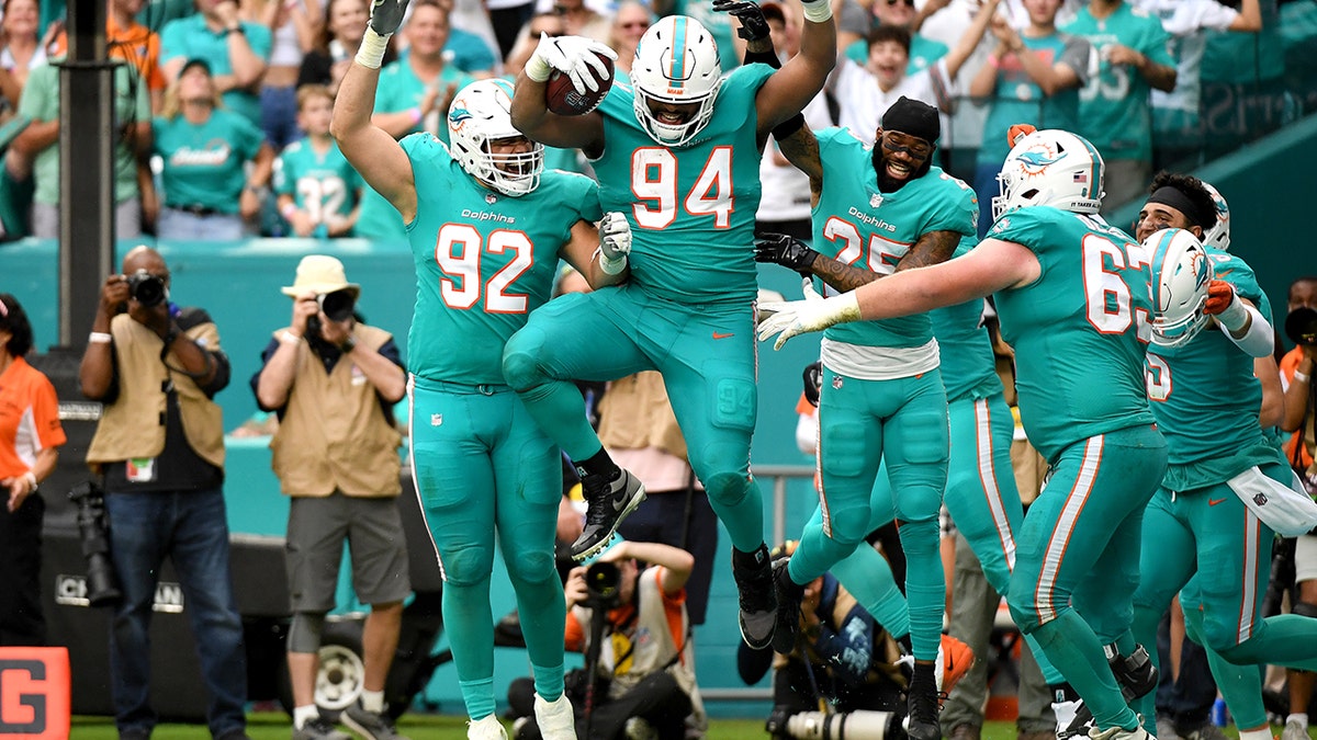 MIAMI GARDENS, FLORIDA - DECEMBER 19: Christian Wilkins #94 of the Miami Dolphins celebrates with teammates after scoring on a touchdown reception against the New York Jets in the fourth quarter at Hard Rock Stadium on December 19, 2021 in Miami Gardens, Florida.