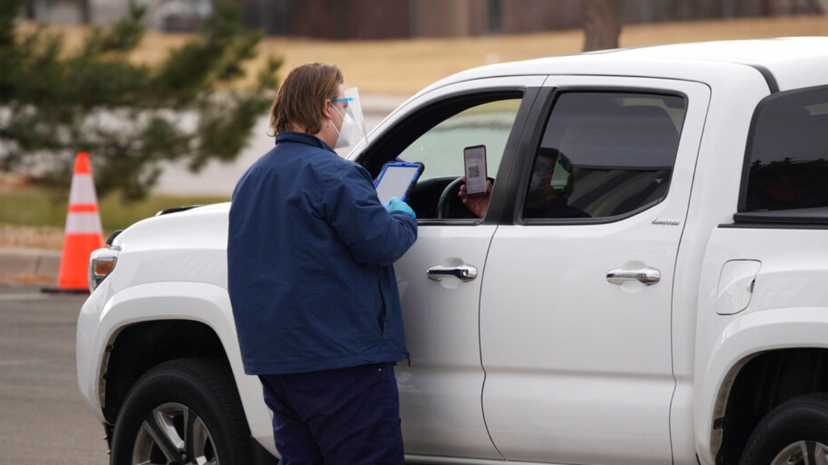 A worker checks in a client at a drive-up COVID-19 testing station outside the justice center Thursday, Dec. 9, 2021, in Castle Rock, Colo. 