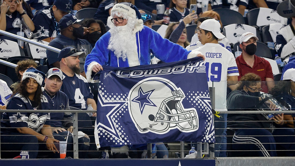 A fan dressed in a holiday costume cheers as the Dallas Cowboys and Washington Football Team warm up before the first half of an NFL football game in Arlington, Texas