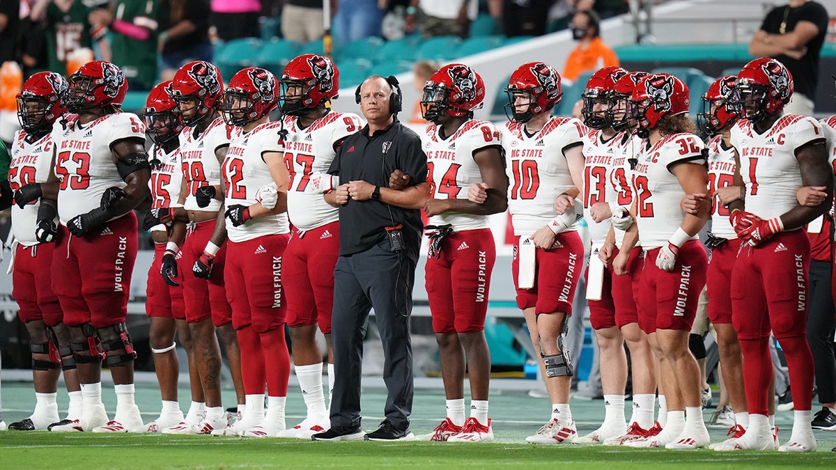 Head coach Dave Doeren of the North Carolina State Wolfpack stands with the team during the national anthem prior to the game against the Miami Hurricanes at Hard Rock Stadium on Oct. 23, 2021, in Miami Gardens, Florida.