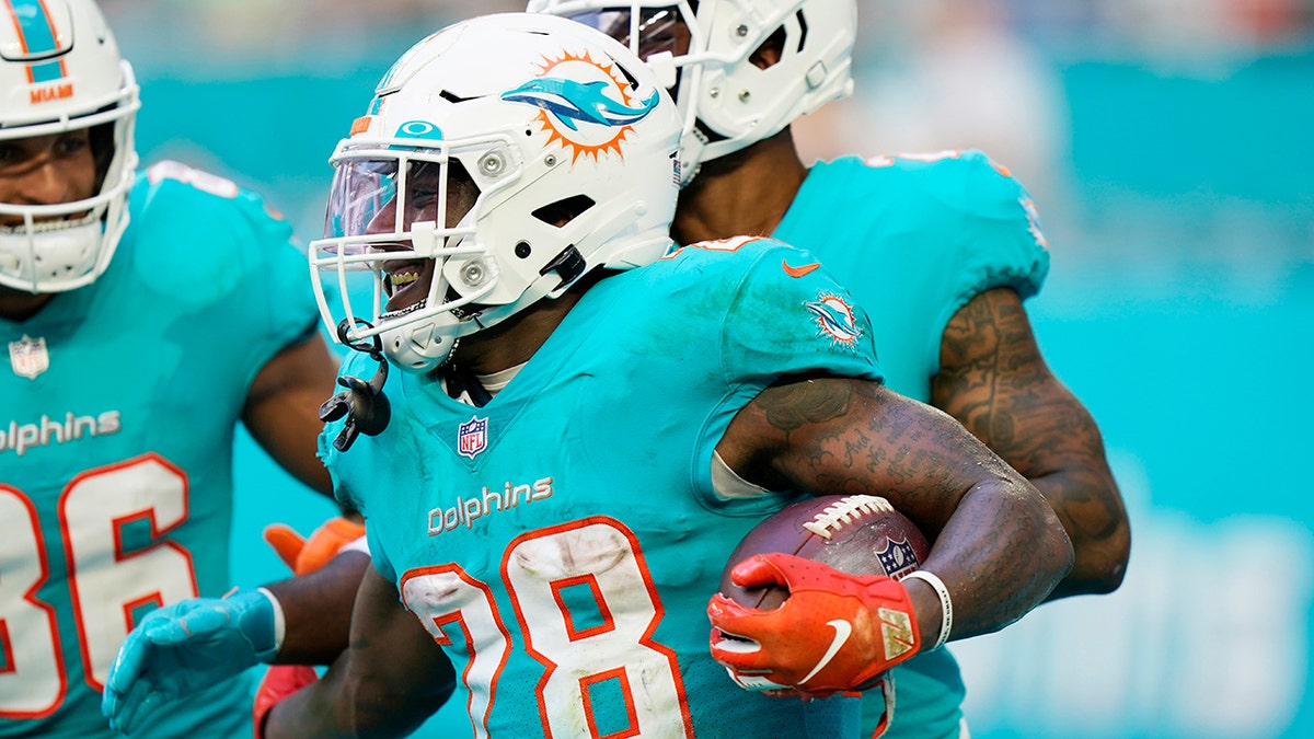 Miami Dolphins running back Duke Johnson (28) is congratulated by teammates after scoring a touchdown during the second half of an NFL football game against the New York Jets, Sunday, Dec. 19, 2021, in Miami Gardens, Fla.