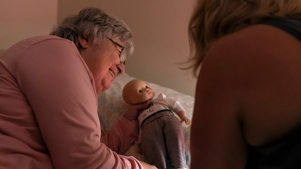 Betty Bednarowski, left, sets her doll on a pillow as her daughter, Susan Ryder, tucks her into bed for the night, Monday, Nov. 29, 2021, in Rotterdam Junction, New York. 