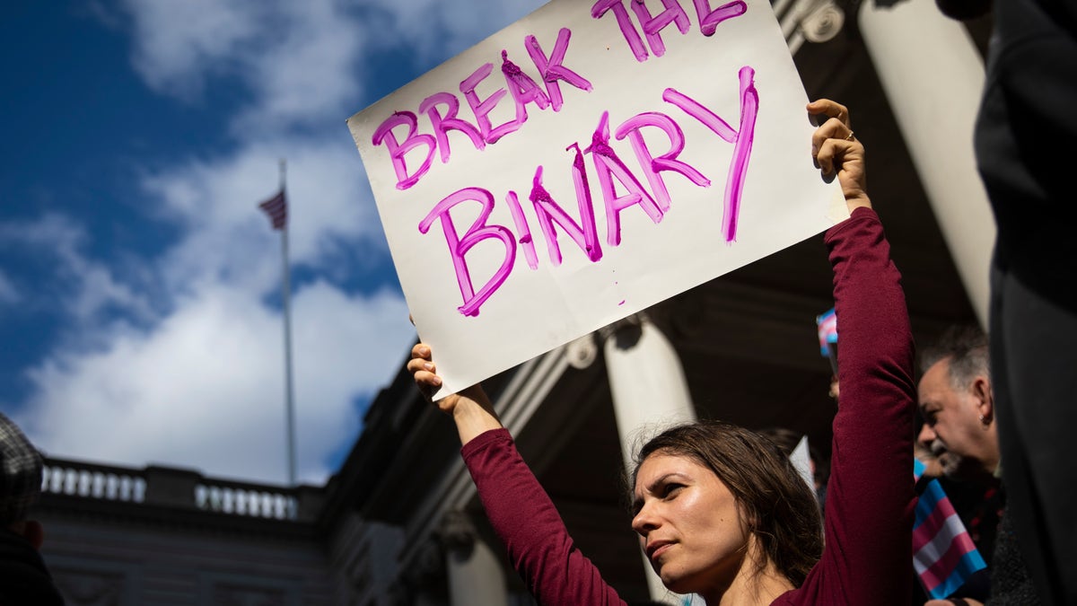 Photo showing LGBTQ activist in NYC holding sign reading "break the binary"