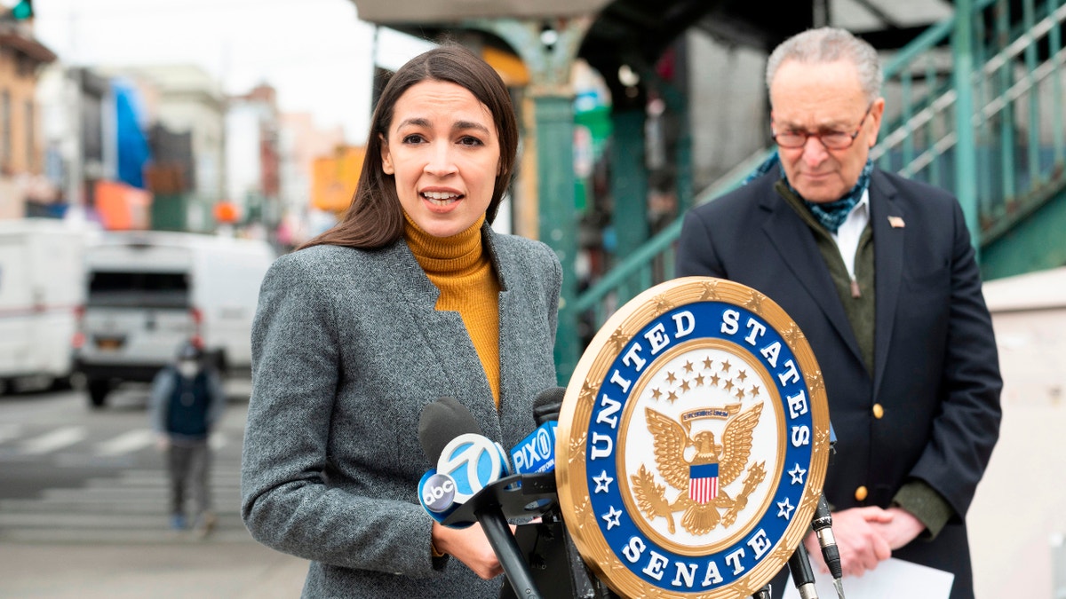 Democratic Rep. Alexandria Ocasio-Cortez of New York speaks as Senate Minority Leader Chuck Schumer listens during a press conference in the Corona neighborhood of Queens on April 14, 2020, in New York City.