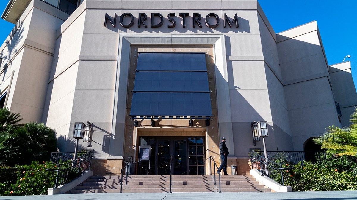 A security guard stands watch outside a Nordstrom store after an organized group of thieves attempted a smash-and-grab attack, Nov. 23, 20201 in Los Angeles.