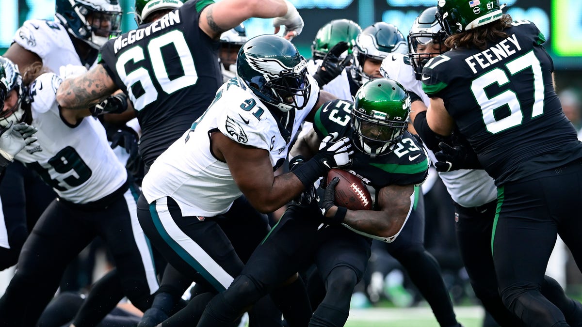 Tevin Coleman (23) of the New York Jets runs the ball and is tackled by Fletcher Cox (91) of the Philadelphia Eagles during the second quarter at MetLife Stadium on Dec. 5, 2021, in East Rutherford, New Jersey. 