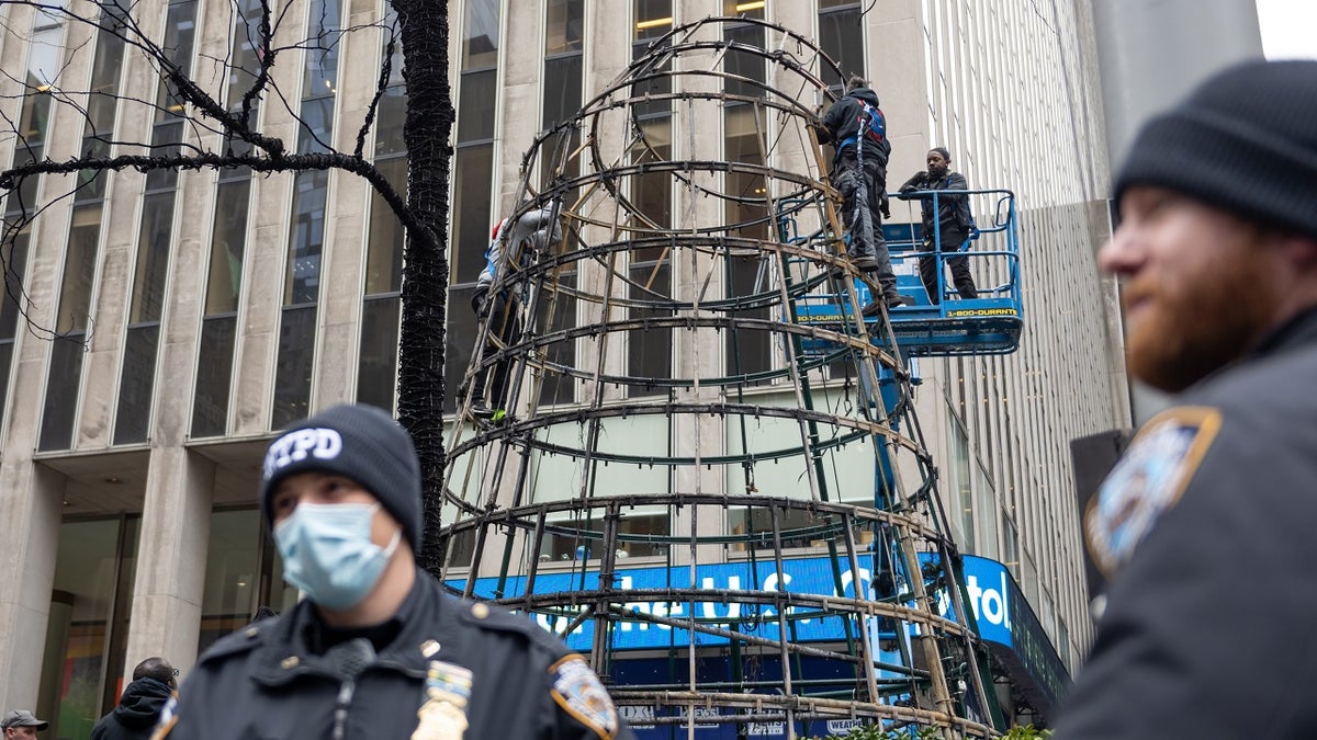 Workers disassemble the Christmas tree outside News Corporation at Fox Square after an arsonist lit the tree on fire Dec. 8, 2021 in New York City. 