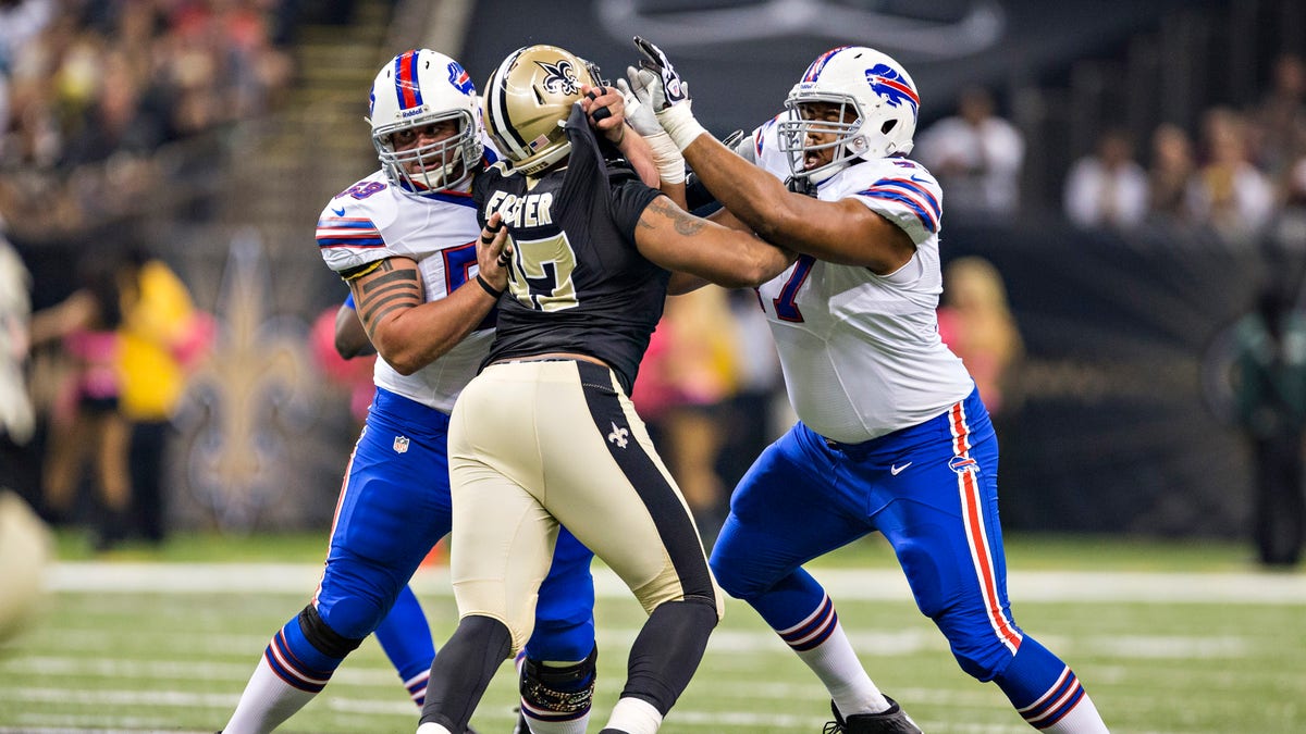Doug Legursky (59) and Cordy Glenn (77) of the Buffalo Bills blocks Glenn Foster (97) of the New Orleans Saints at Mercedes-Benz Superdome on Oct. 27, 2013, in New Orleans, Louisiana. 