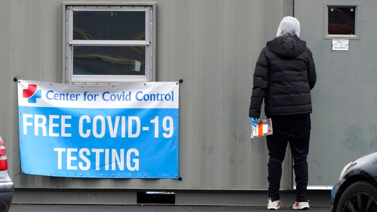 A sign about COVID-19 testing is displayed outside of COVID-19 testing site as a health walker collects testing tube in Wheeling, Ill., Friday, Dec. 3, 2021. A week after Thanksgiving, Illinois on Thursday reported this year's highest daily total of new coronavirus cases, while COVID-19 hospitalizations have risen higher than any point since last winter. (AP Photo/Nam Y. Huh) 
