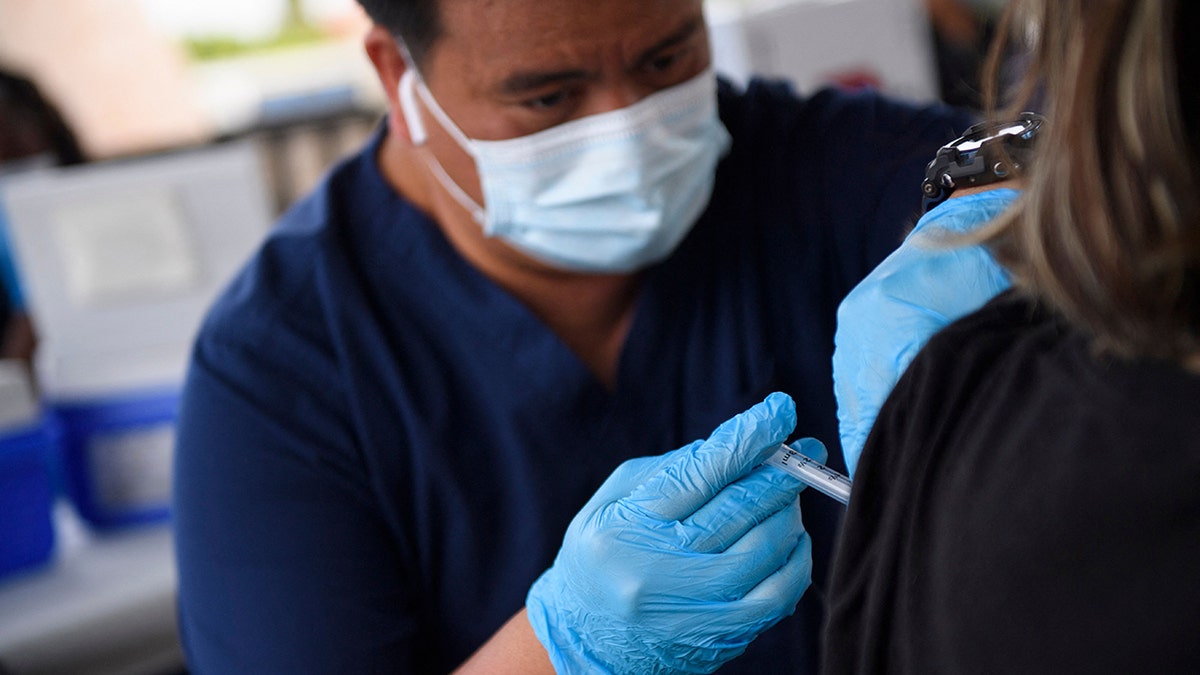 A nurse administers a dose of the Pfizer Covid-19 vaccine to high school student during a City of Long Beach Public Health Covid-19 mobile vaccination clinic at the California State University Long Beach. (Photo by PATRICK T. FALLON/AFP via Getty Images)