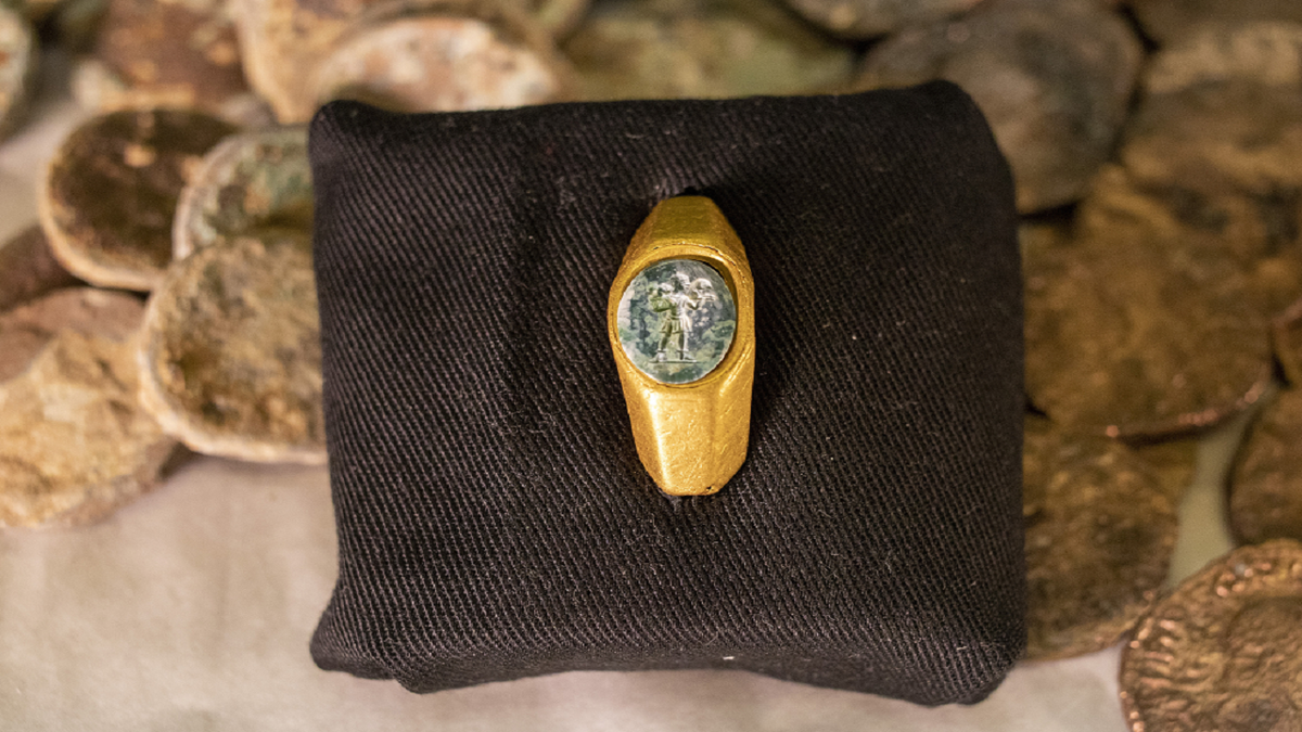 A Roman gold ring, its green gemstone carved with the figure of a shepherd carrying a sheep on his shoulders, is on display with coins that where found near the ancient city of Caesarea, dated to the Roman and Mamluk periods, around 1,700 and 600 years ago, in Jerusalem on Wednesday. 