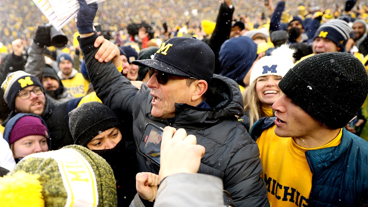 Head Coach Jim Harbaugh of the Michigan Wolverines celebrates with fans after defeating the Ohio State Buckeyes at Michigan Stadium on November 27, 2021 in Ann Arbor, Michigan.