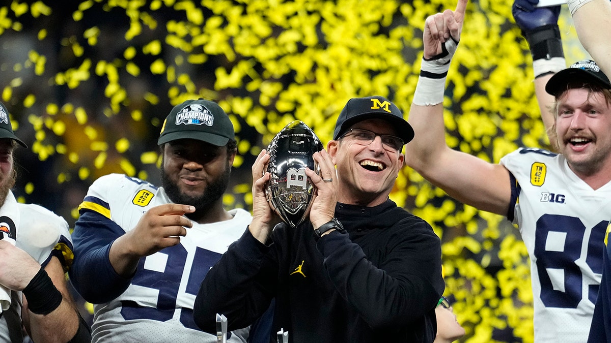 Jim Harbaugh holds trophy