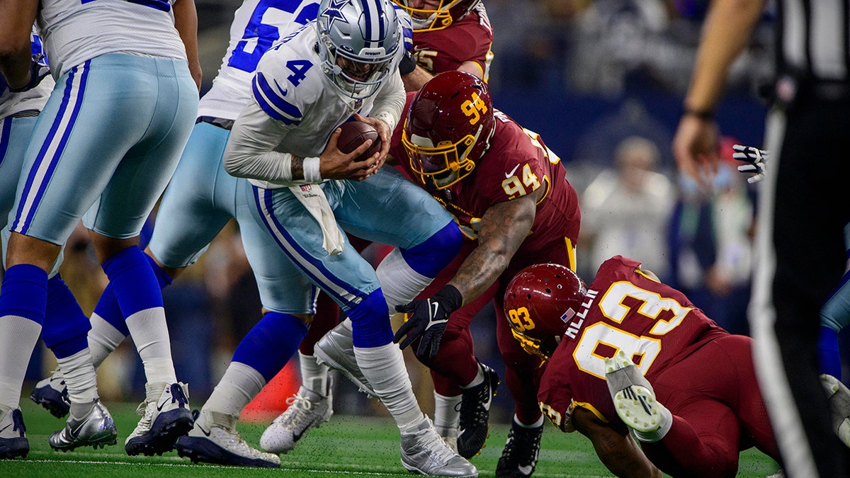 Dallas Cowboys quarterback Dak Prescott (4) is tackled by Washington Football Team defensive tackle Daron Payne (94) and defensive tackle Jonathan Allen (93) during the first quarter at AT&T Stadium.