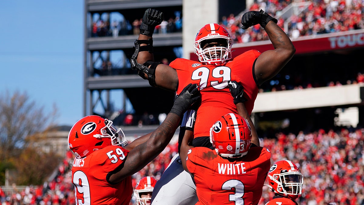 Georgia defensive lineman Jordan Davis (99) is lifted into the air by running back Zamir White (3) and offensive lineman Justin Shaffer (54) after scoring a touchdown in the first half of an NCAA college football game against Charleston Southern, Saturday, Nov. 20, 2021, in Athens, Ga.