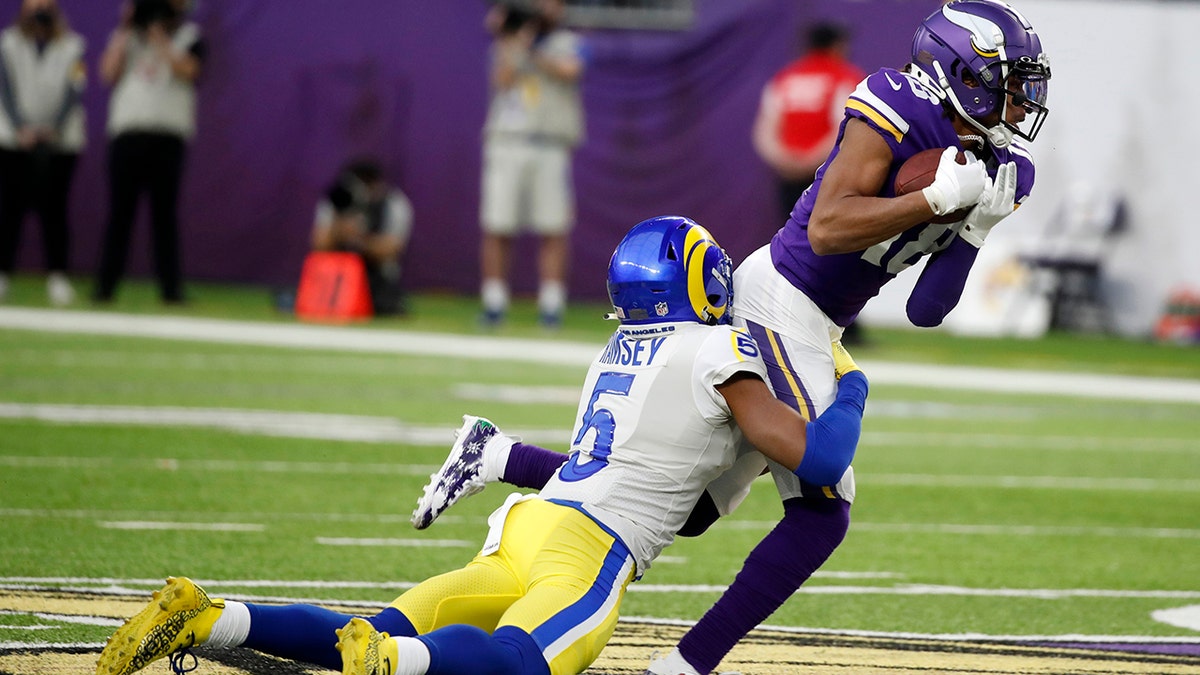 Minnesota Vikings wide receiver Justin Jefferson (18) catches a pass ahead of Los Angeles Rams cornerback Jalen Ramsey (5) during the second half of an NFL football game, Sunday, Dec. 26, 2021, in Minneapolis.